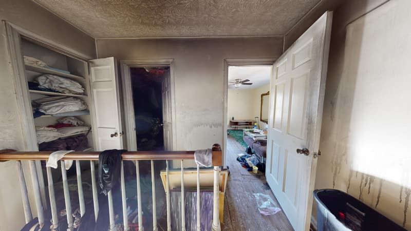 Second floor hallway before restoration showing heavy soot on walls and damaged flooring
