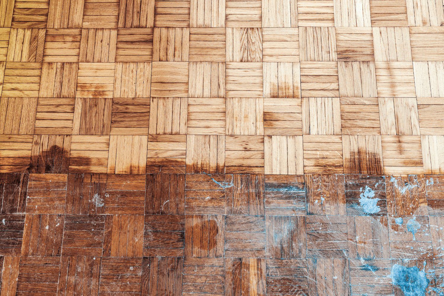 A partially refinished wooden floor, showing the difference between the lighter, sanded area and the darker, original finish.