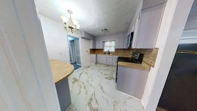 Kitchen after fire restoration with new marble-look flooring and updated gray cabinetry