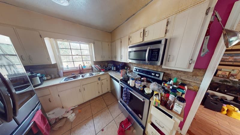 Second kitchen angle before restoration showing soot-covered cabinets and smoke staining