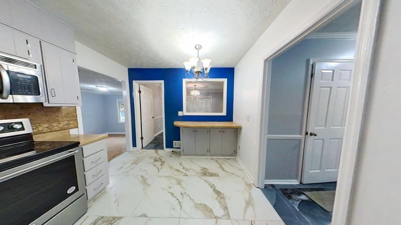 Third kitchen angle after restoration with blue accent wall, new flooring, and open layout