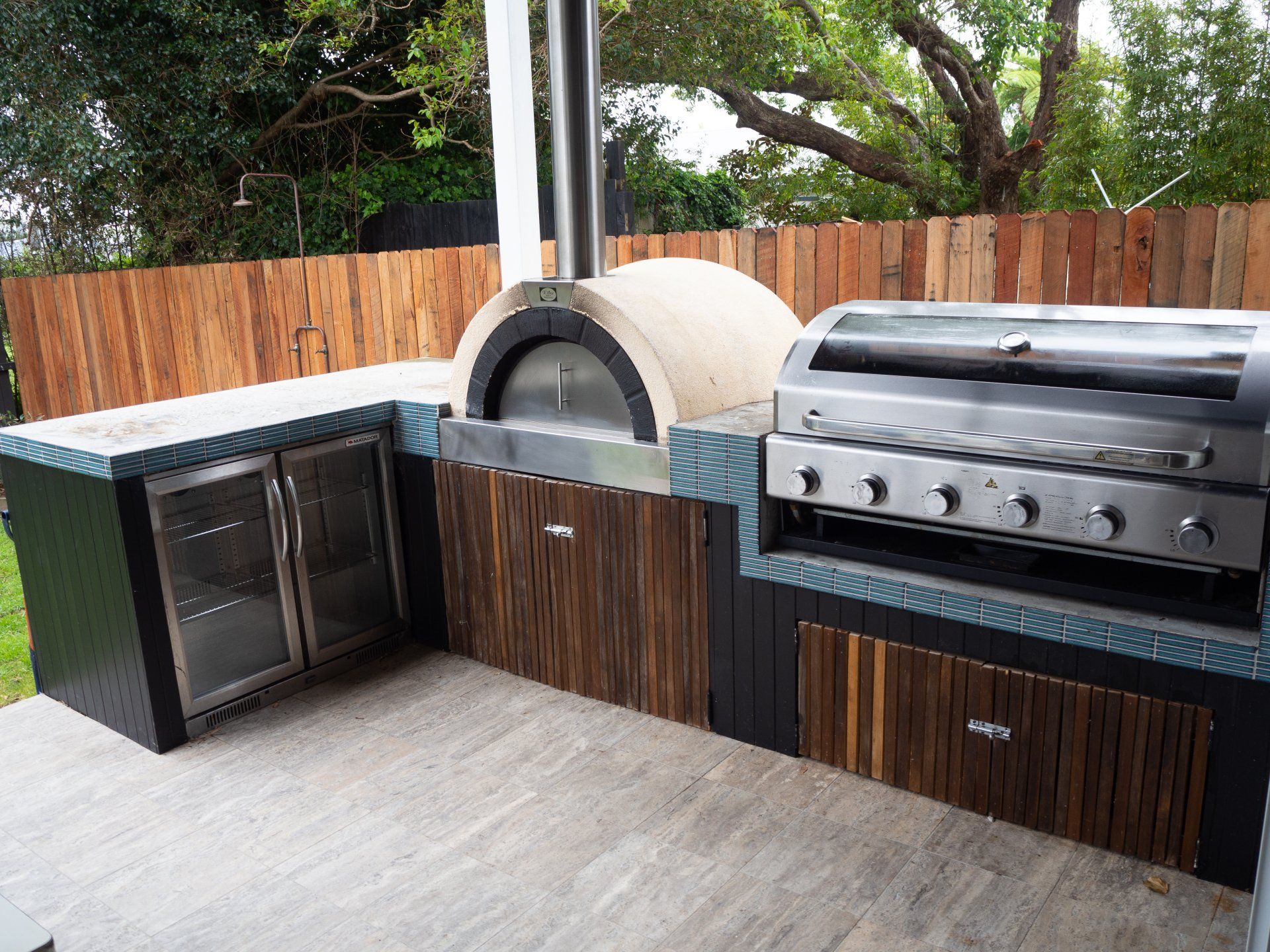 An outdoor kitchen with a pizza oven , grill and refrigerator.  bundarwa beach house Currarong Beach NSW
