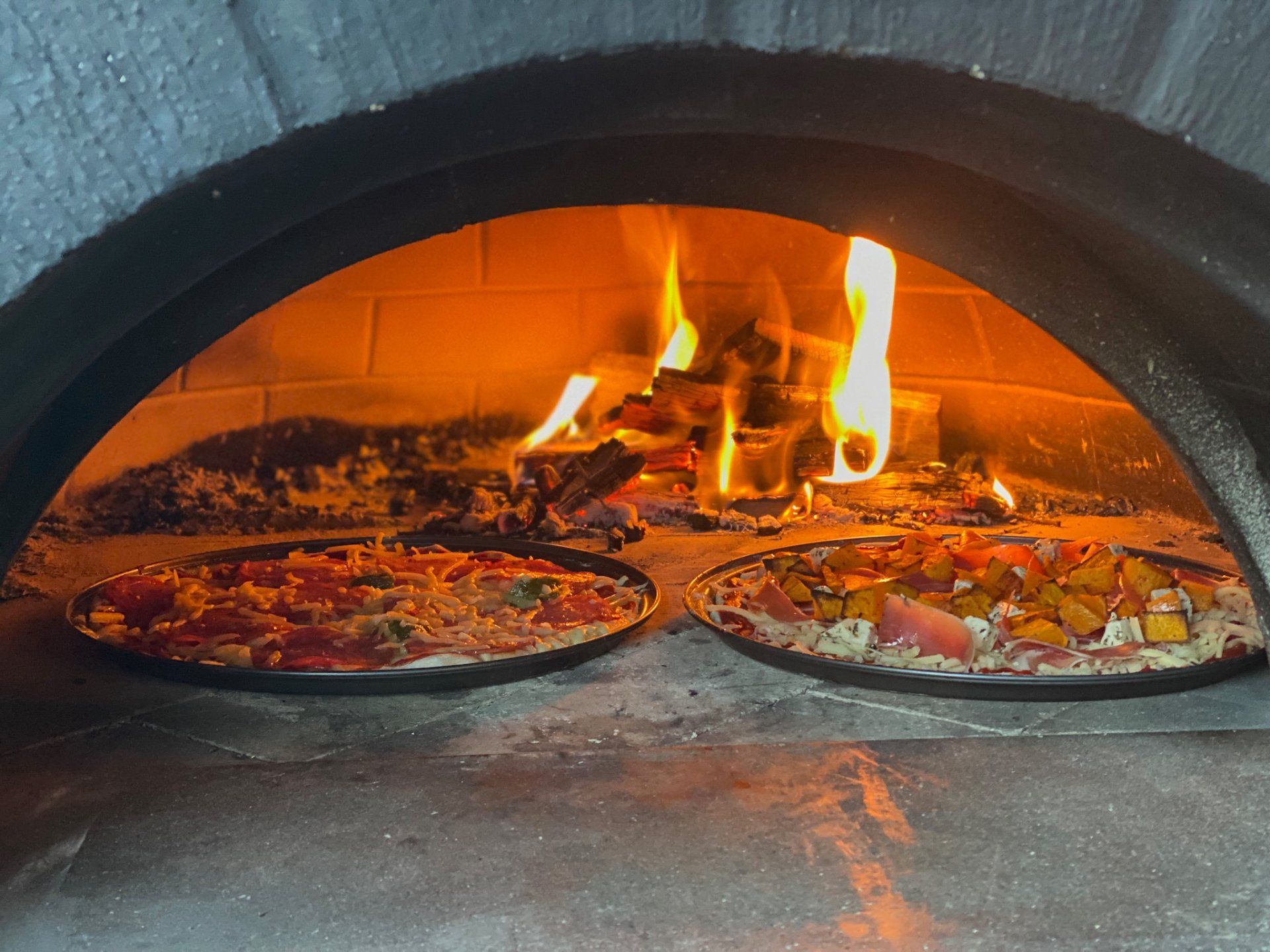 Two pizzas are being cooked in a brick oven Currarong Beach NSW