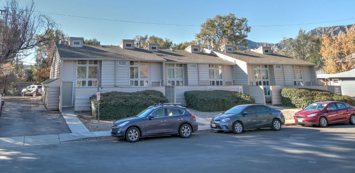 Aerial view of a campus with red-tiled roofs, green trees, and beige buildings.