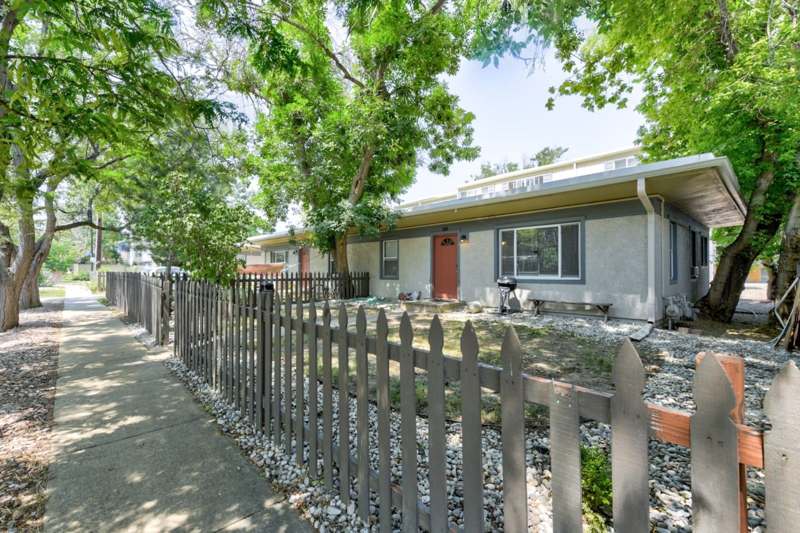 Aerial view of a city next to a river lined with trees. Cloudy sky, buildings, and a bridge.