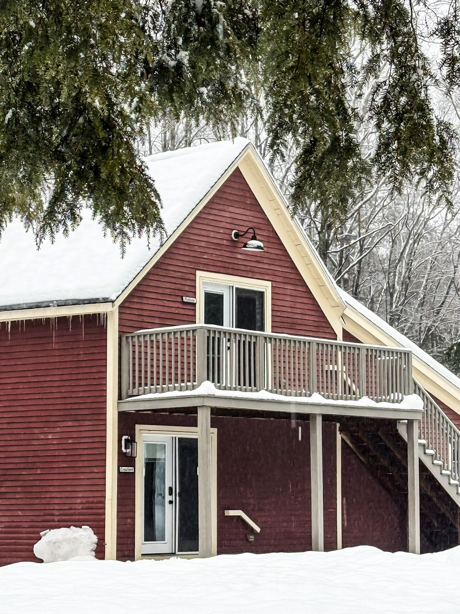 A red house with a balcony is covered in snow.