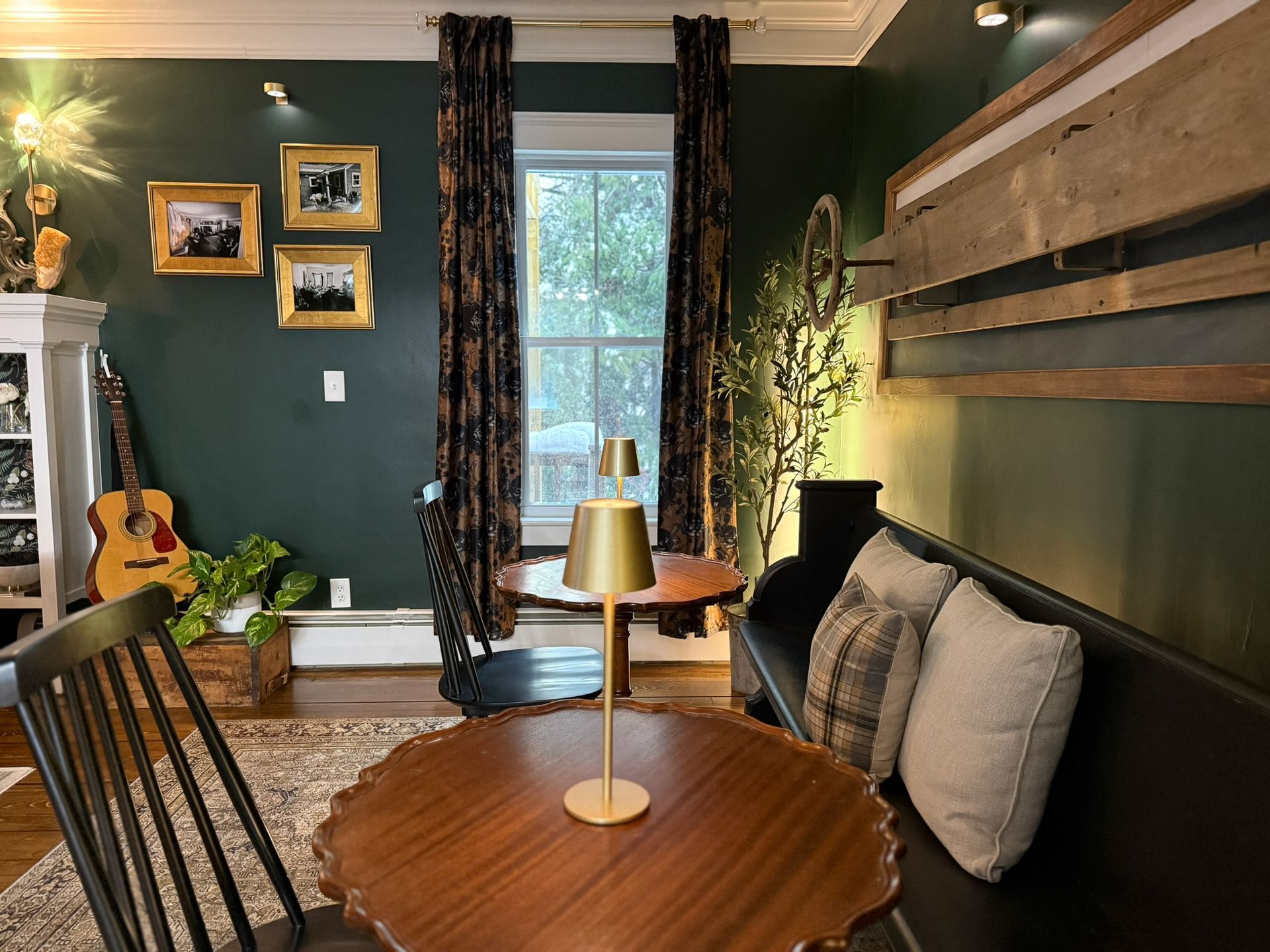 A living room with a table and chairs and a guitar on the wall.