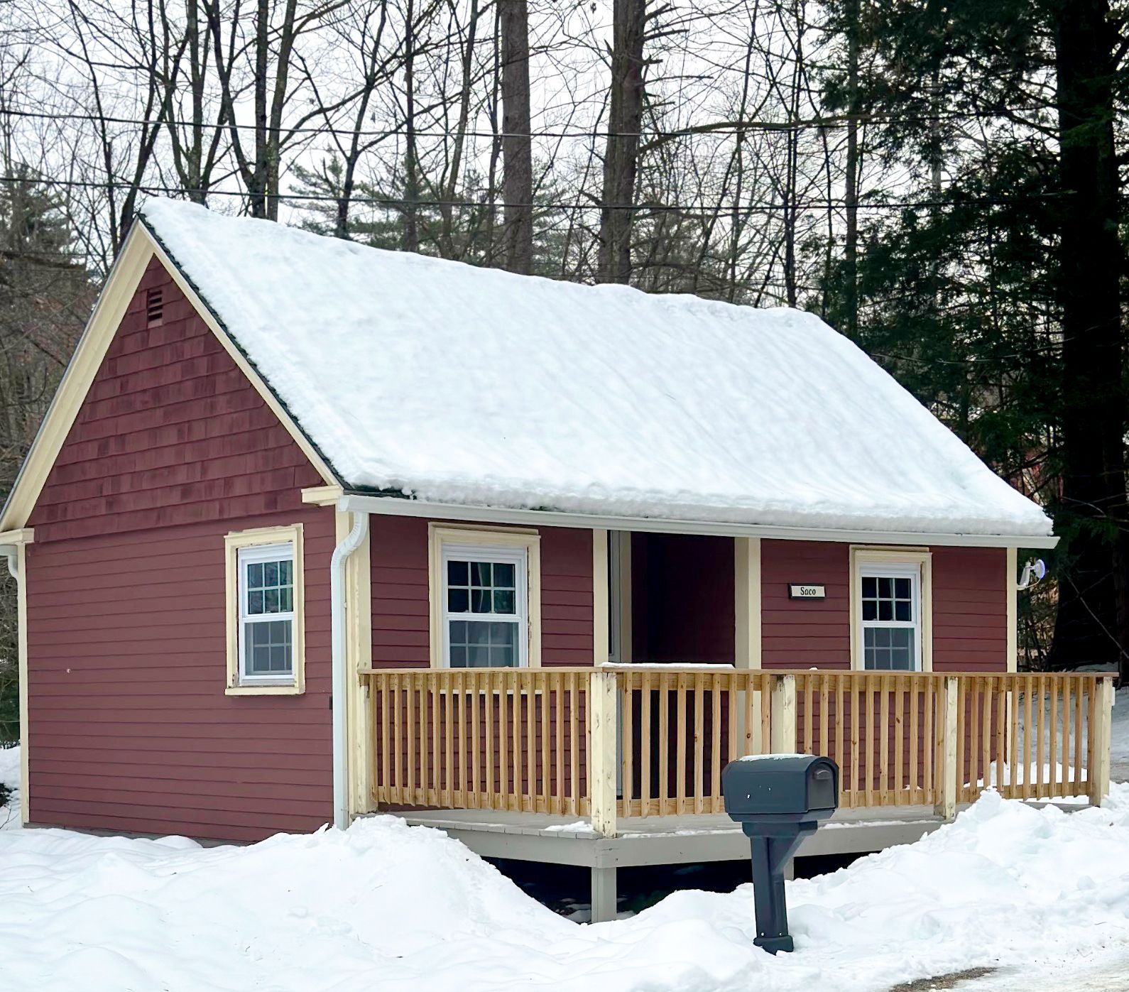 A small red house with a porch and a mailbox