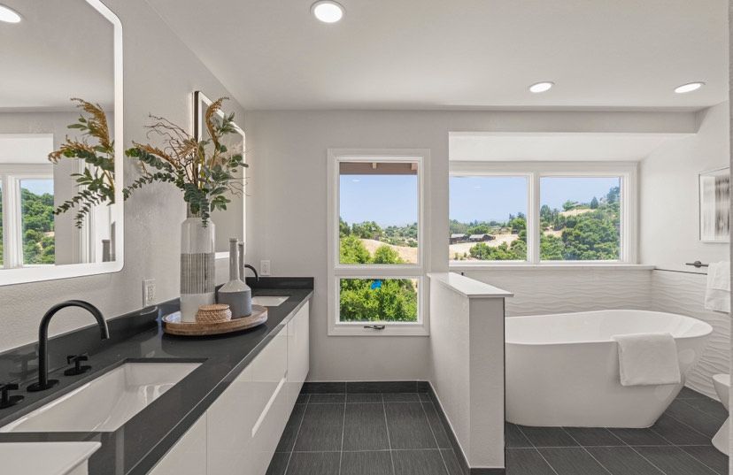 A bathroom with two sinks , a tub and two mirrors.