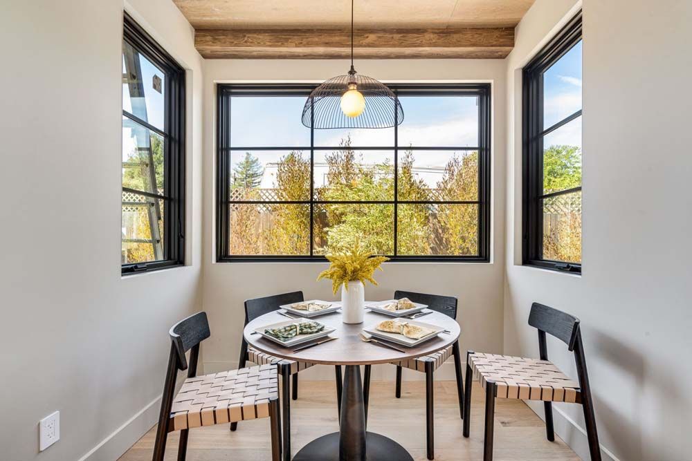 A dining room with a table and chairs in front of a window.