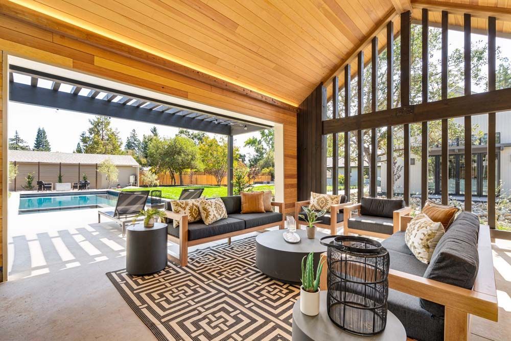 Outdoor living area with wood ceiling, seating, and view of pool.