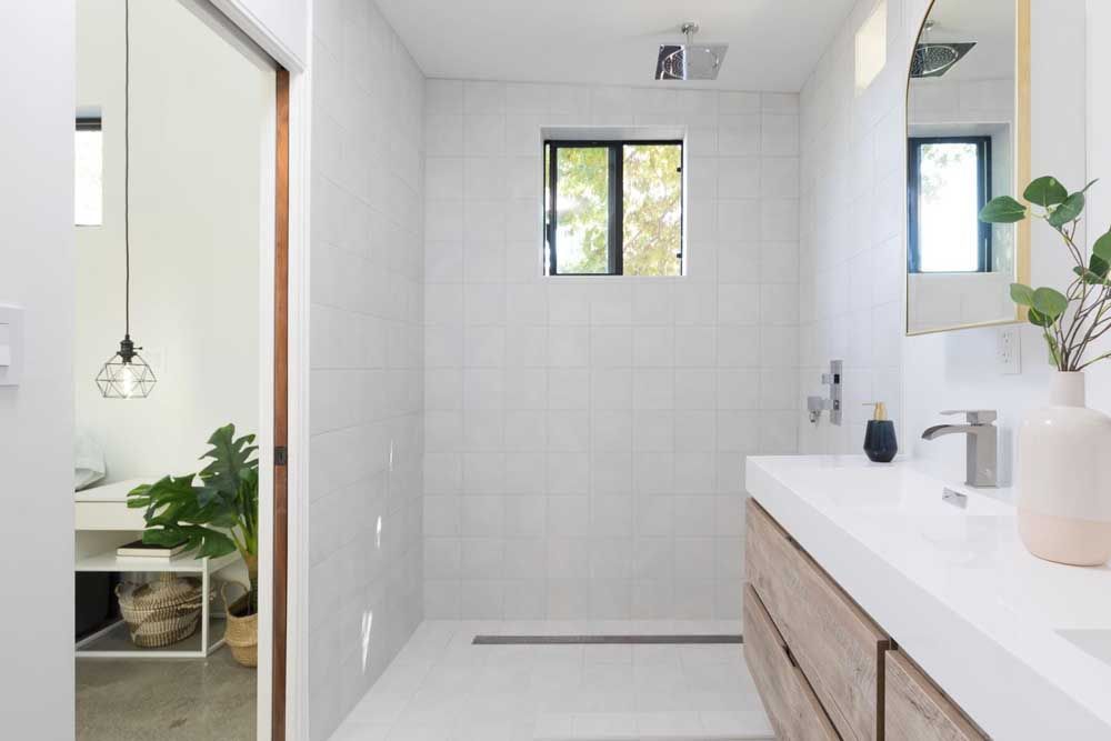 A bathroom with a walk in shower , sink and mirror.
