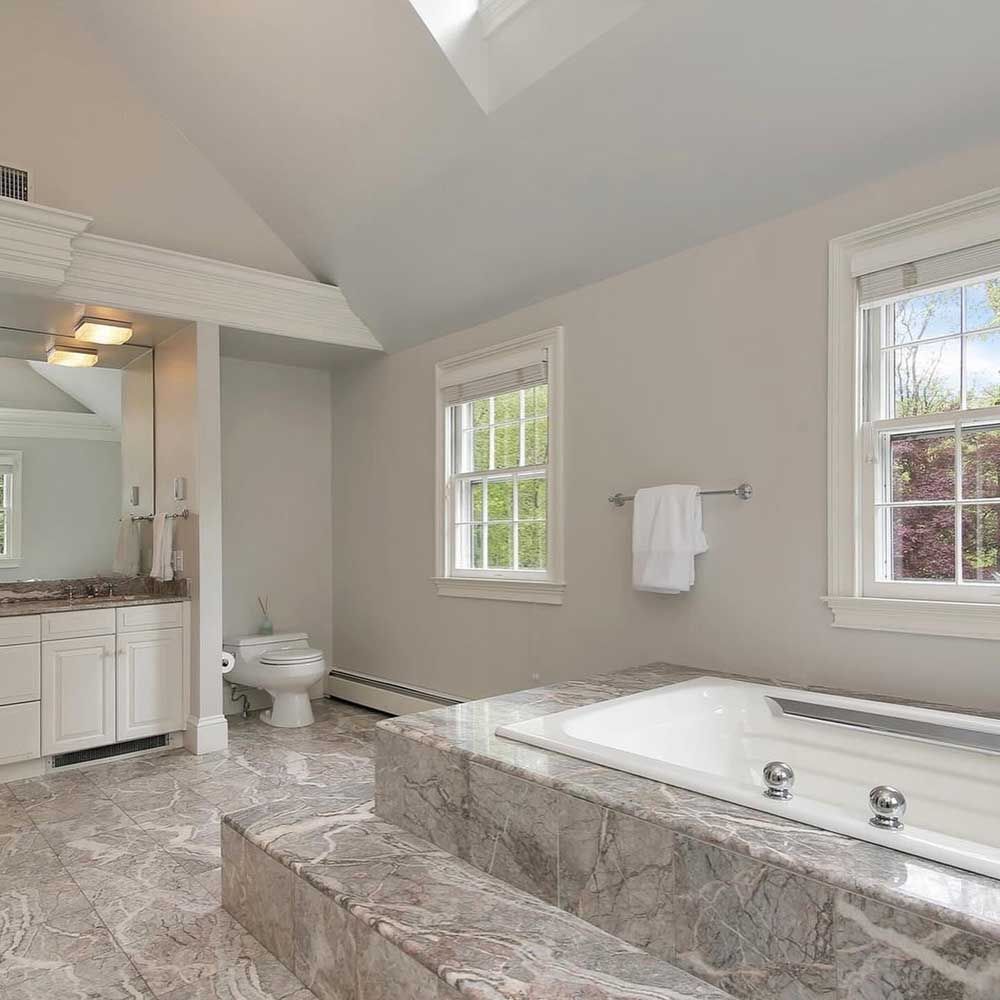 A bathroom with a jacuzzi tub , toilet , sink and mirror.