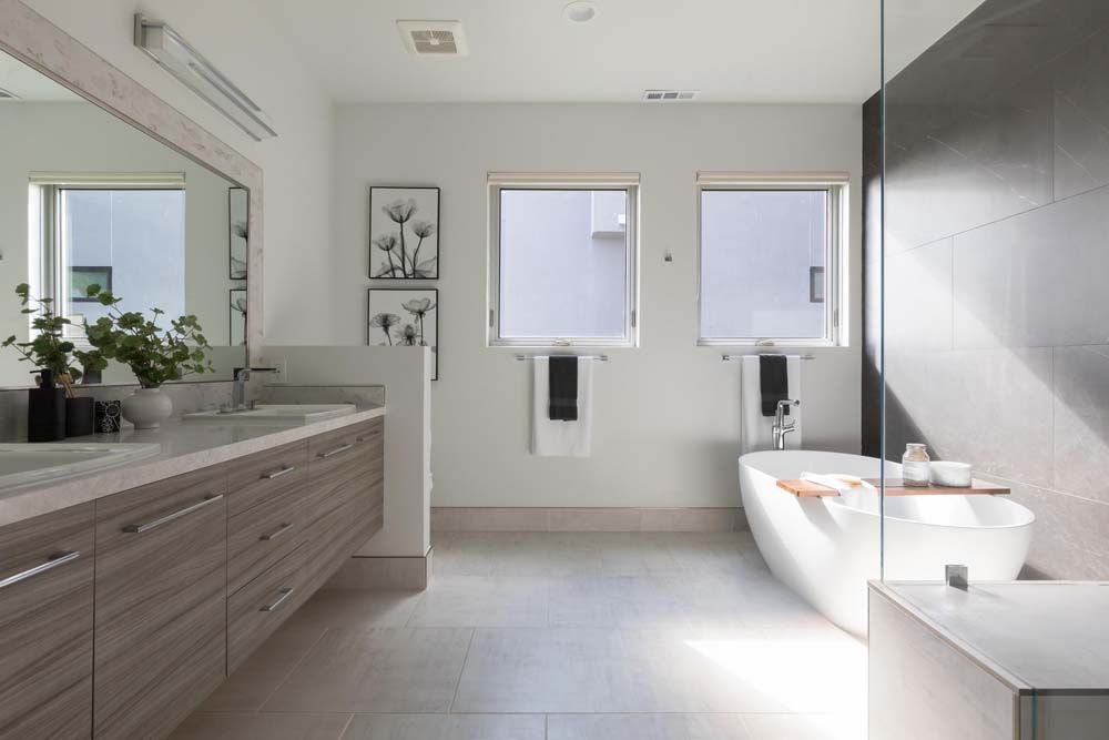 A bathroom with two sinks , a tub and a mirror.