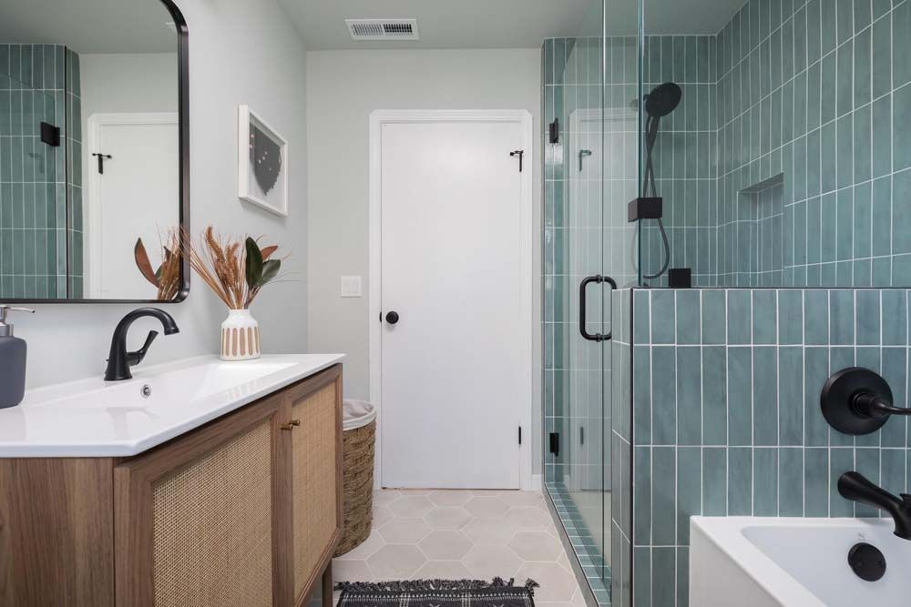 A bathroom with a sink , mirror , tub and shower.