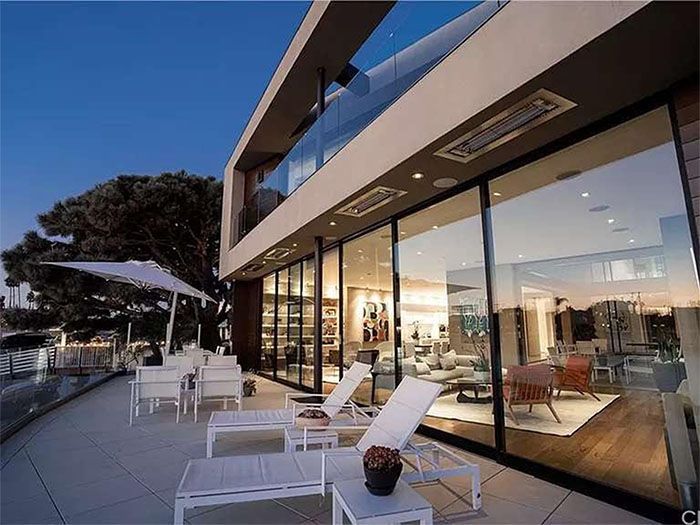 A large house with a lot of windows and chairs on the patio