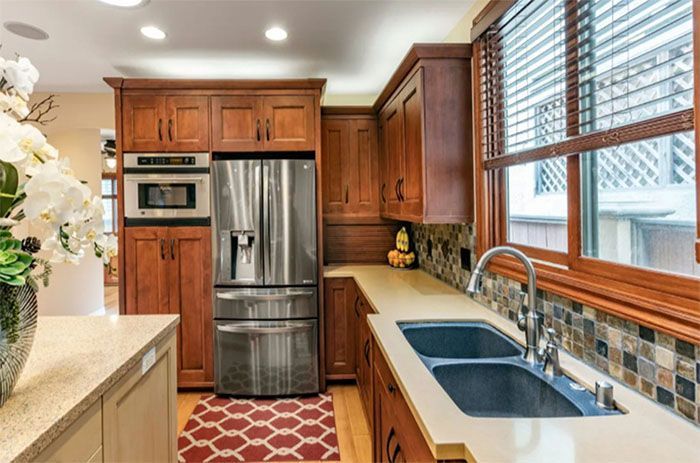 A kitchen with stainless steel appliances , wooden cabinets , a sink and a refrigerator.