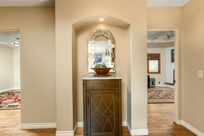 A hallway in a house with a cabinet and a mirror.