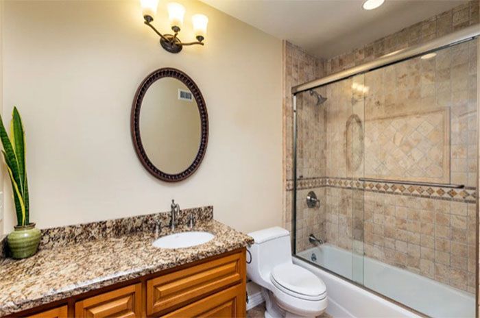 A bathroom with a toilet , sink , mirror and shower.