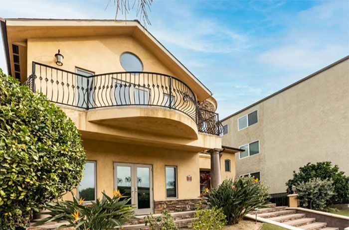 A large house with a balcony and stairs in front of it.