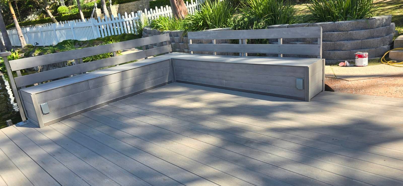 An L-shaped gray deck bench with a backrest on a matching gray composite deck.