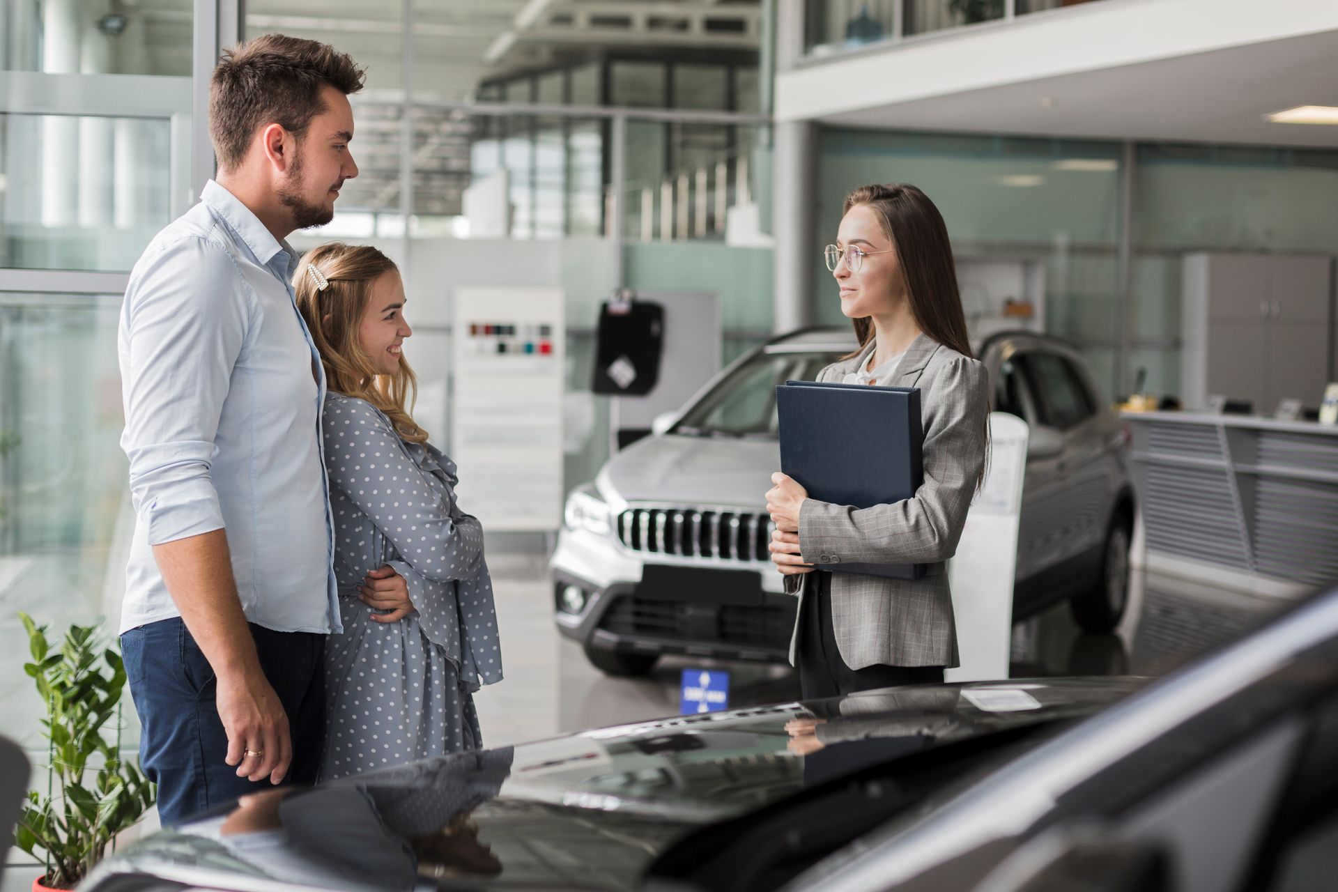 A man and a little girl are looking at a car in a showroom.