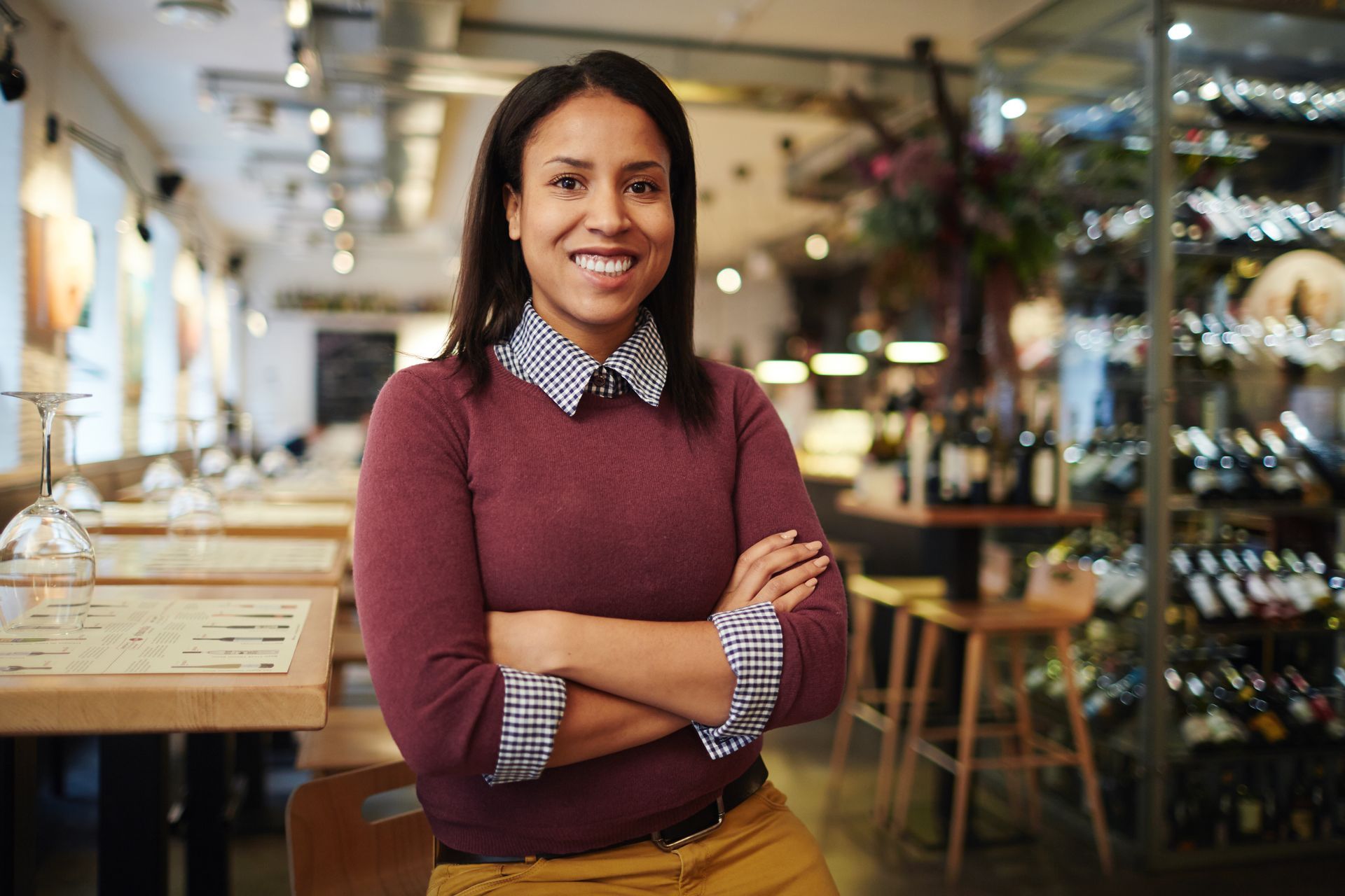 A woman is standing in a restaurant with her arms crossed.