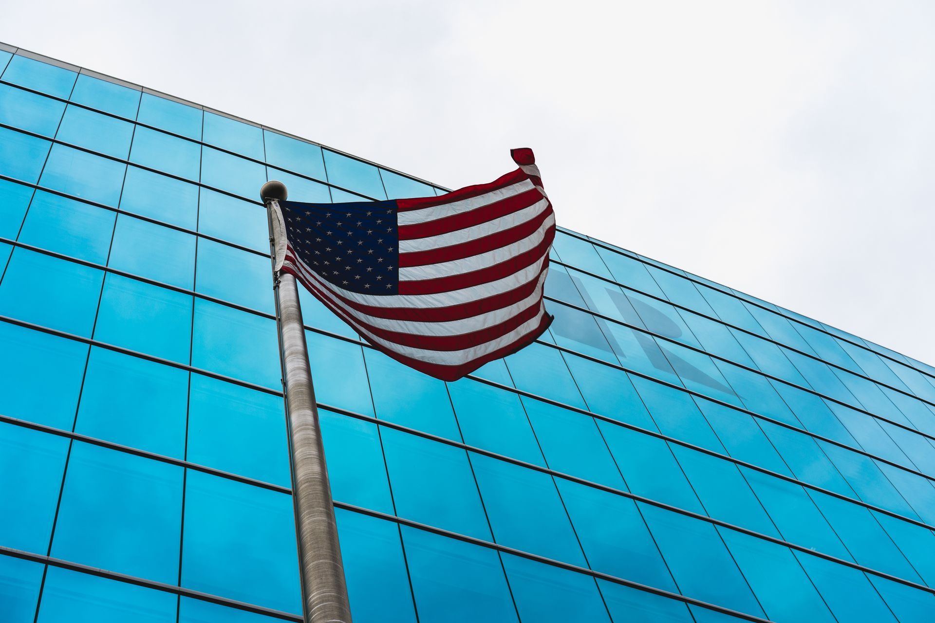 An american flag is flying in front of a blue building