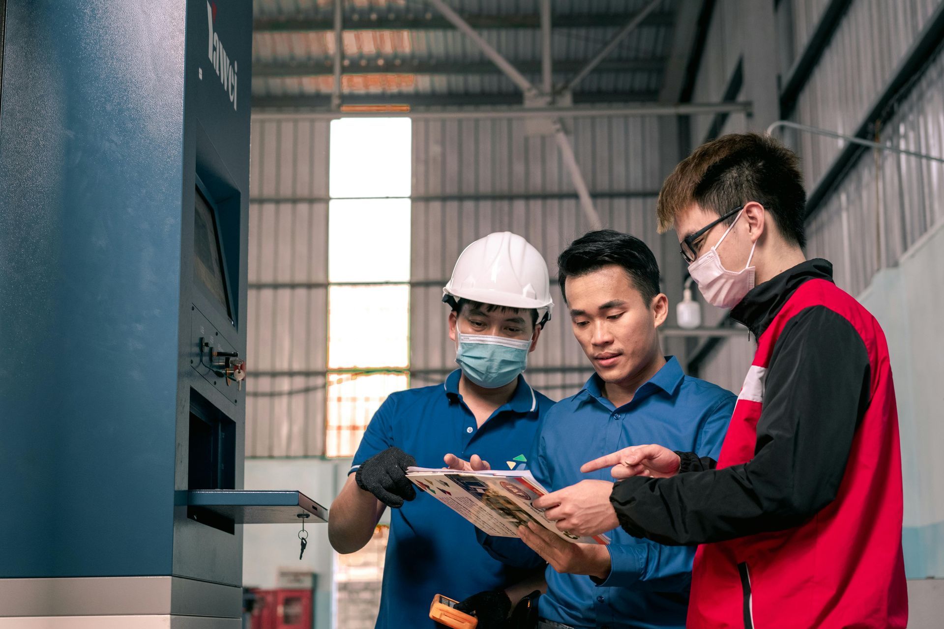 A group of men are looking at a clipboard in a factory.