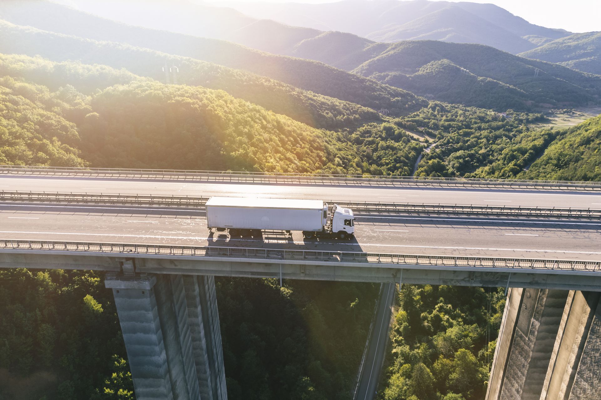 An aerial view of a truck driving over a bridge.