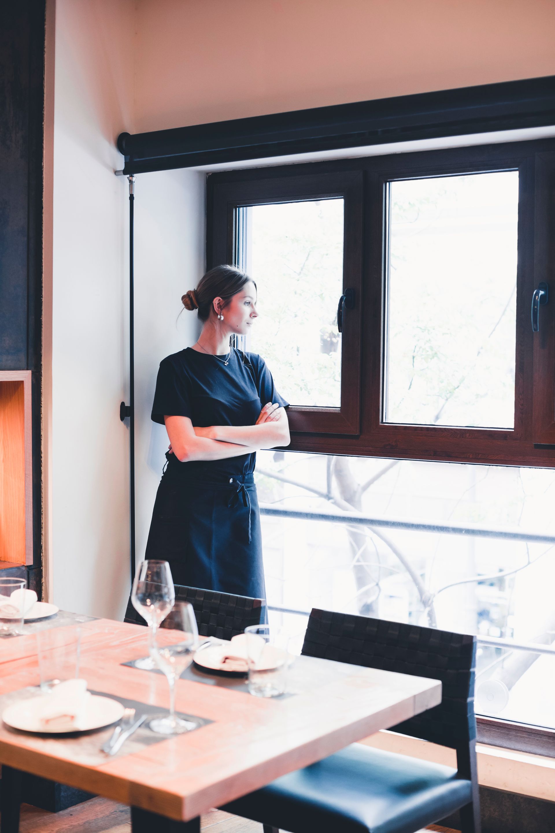 A woman is standing in front of a window in a restaurant.