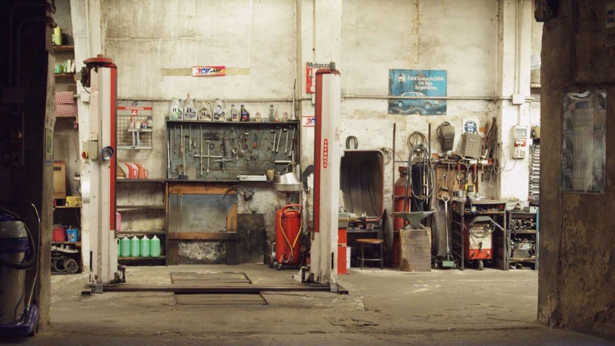 Taller mecánico con elevadores, herramientas y equipos en un antiguo local industrial.