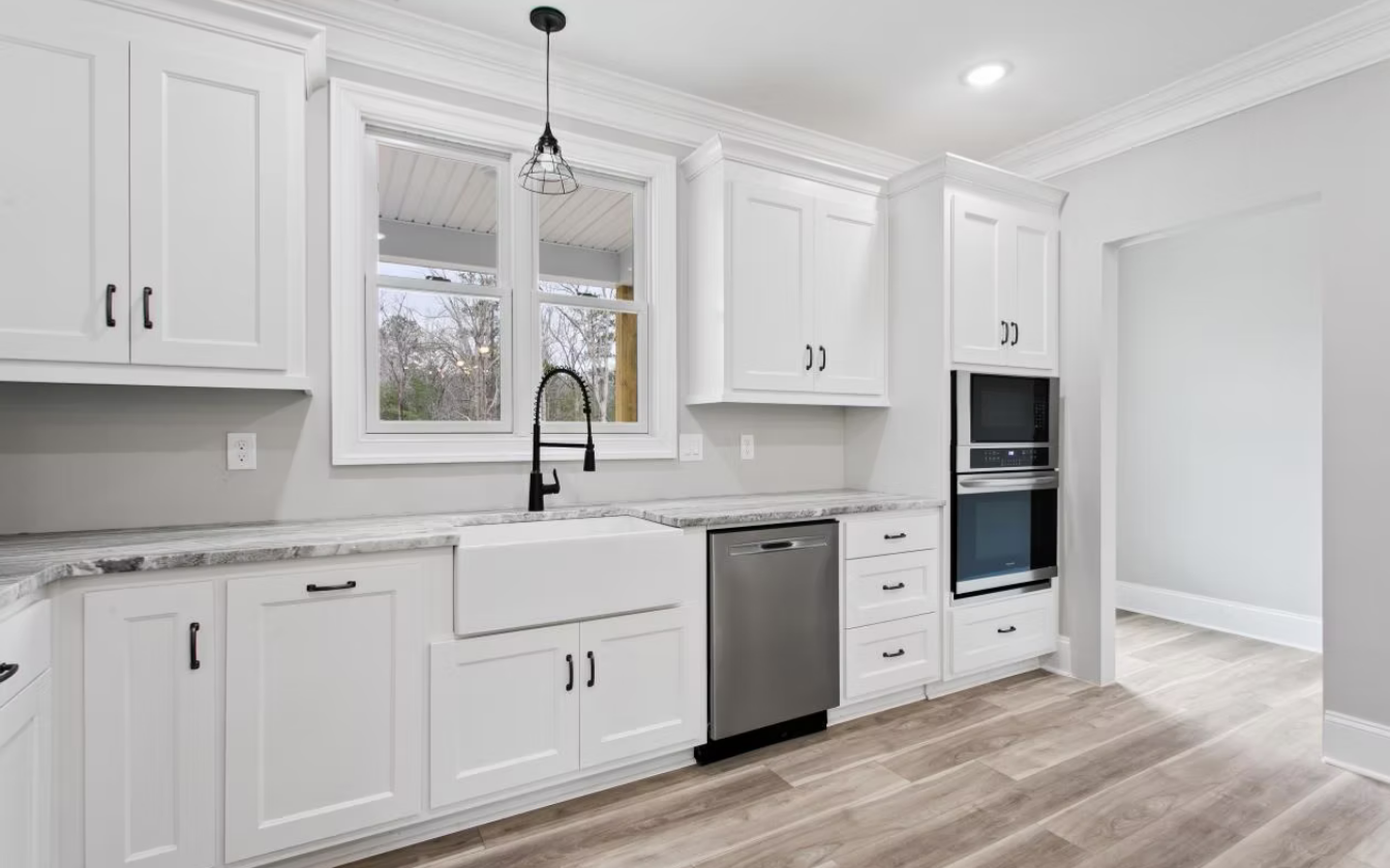 Two tan leather armchairs face a small round table in a cafe, surrounded by lush plants and a copper shelving unit.