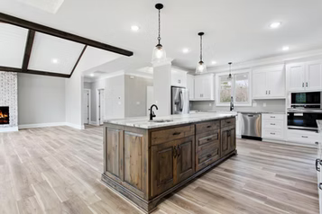 Spacious kitchen with wood island, white cabinets, and stainless steel appliances. Wooden beams and light wood floors.