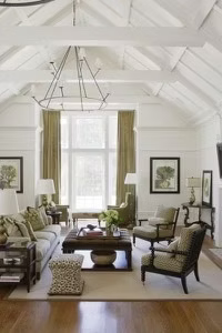Living room with high, white ceiling, olive curtains, and wood furniture.