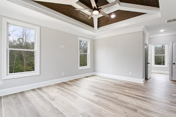 Empty bedroom with light wood floors, gray walls, and a wooden ceiling with a fan.