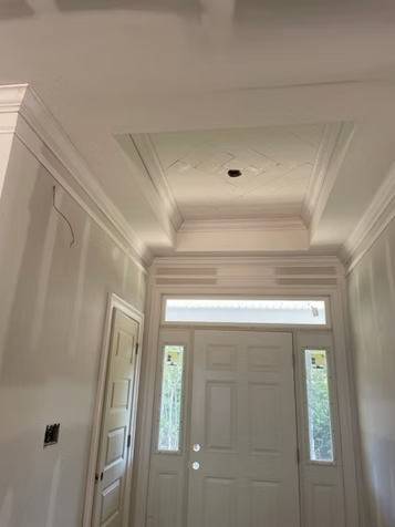 Entrance hall with white door, sidelights, and detailed ceiling molding.
