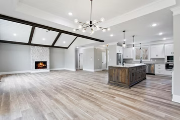 Spacious open-concept living space with fireplace, kitchen island, and light wood flooring.
