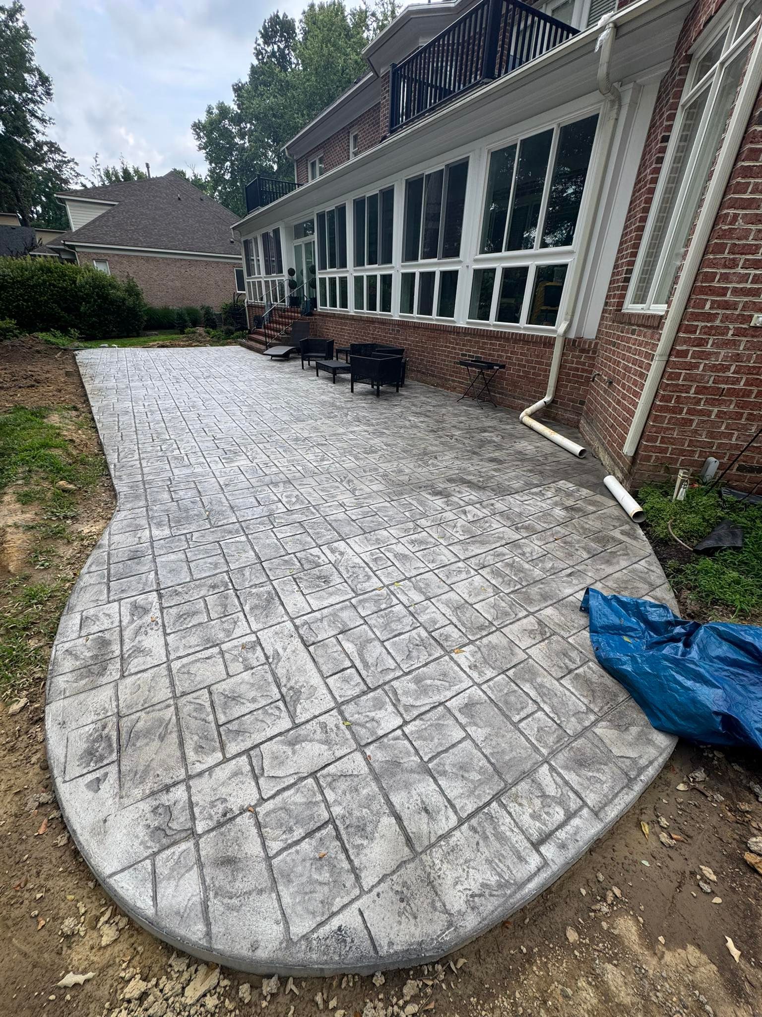 Newly constructed stamped concrete patio next to a brick house.