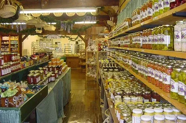 A country store interior with long wooden shelves packed with rows of canned goods, preserves, and jars.