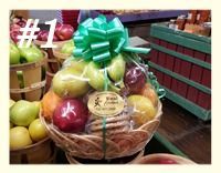 A gift basket filled with assorted fruit and a package of cookies, topped with a large green bow.