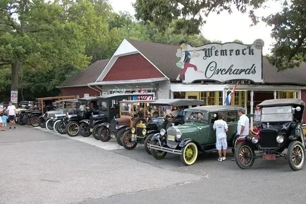 A row of vintage cars parked in front of a rustic building with a sign that reads 