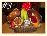 A wicker gift basket containing loaves of bread, bananas, grapes, a nut-filled tart, jam, fruit, and a red bow on top.