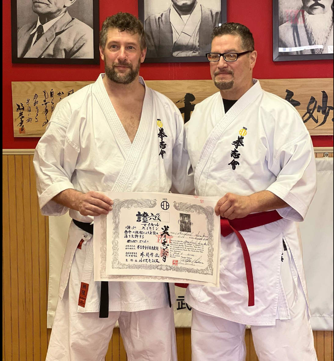 two men in karate uniforms holding a certificate with chinese writing on it
