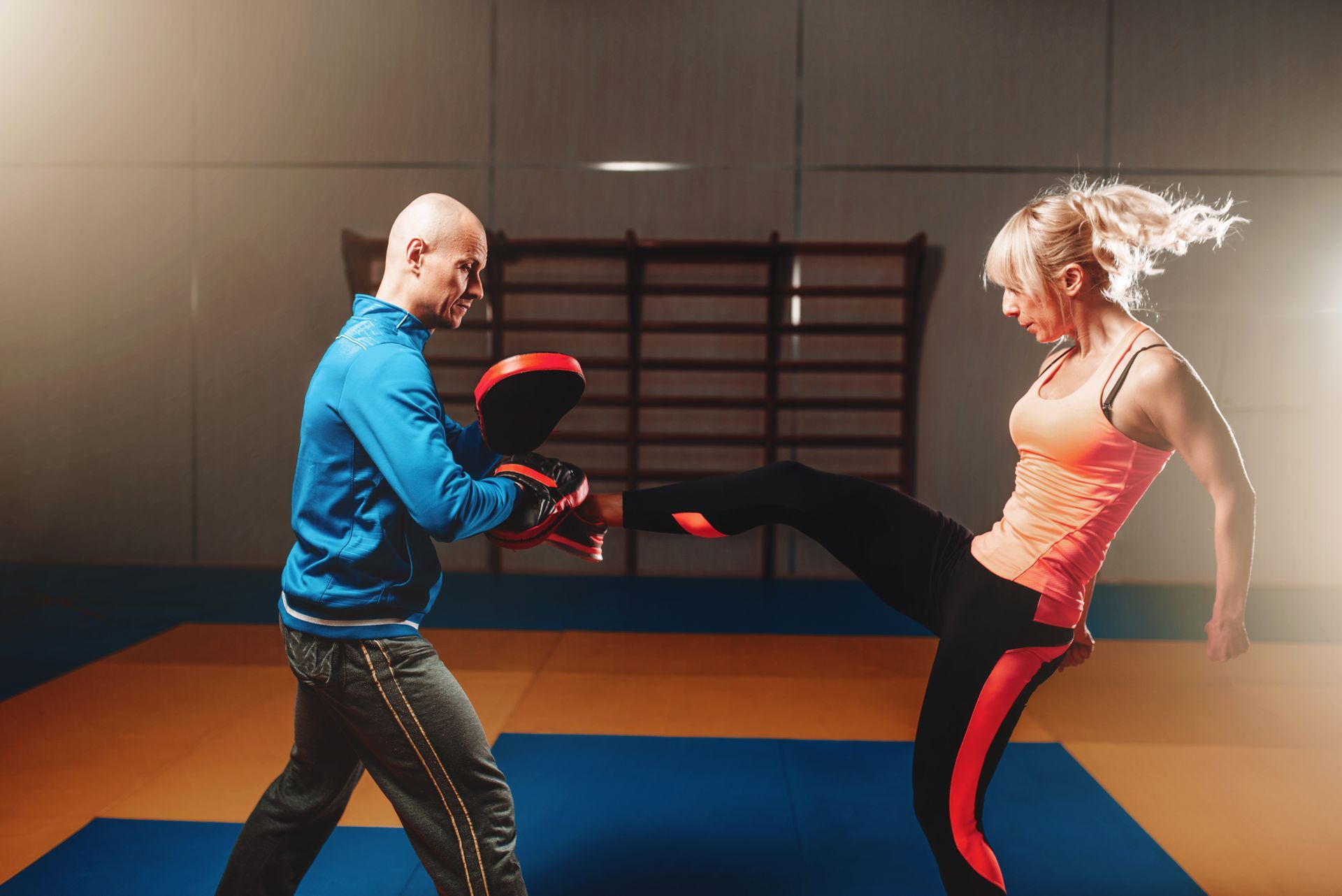 A man and a woman are practicing martial arts in a gym.