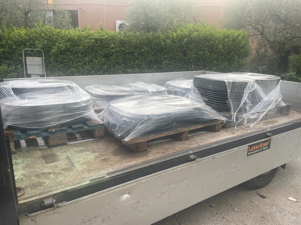 Diversi pallet di lastre di pietra nera impilate e avvolte nella plastica vengono caricati sul cassone di un camion a pianale.