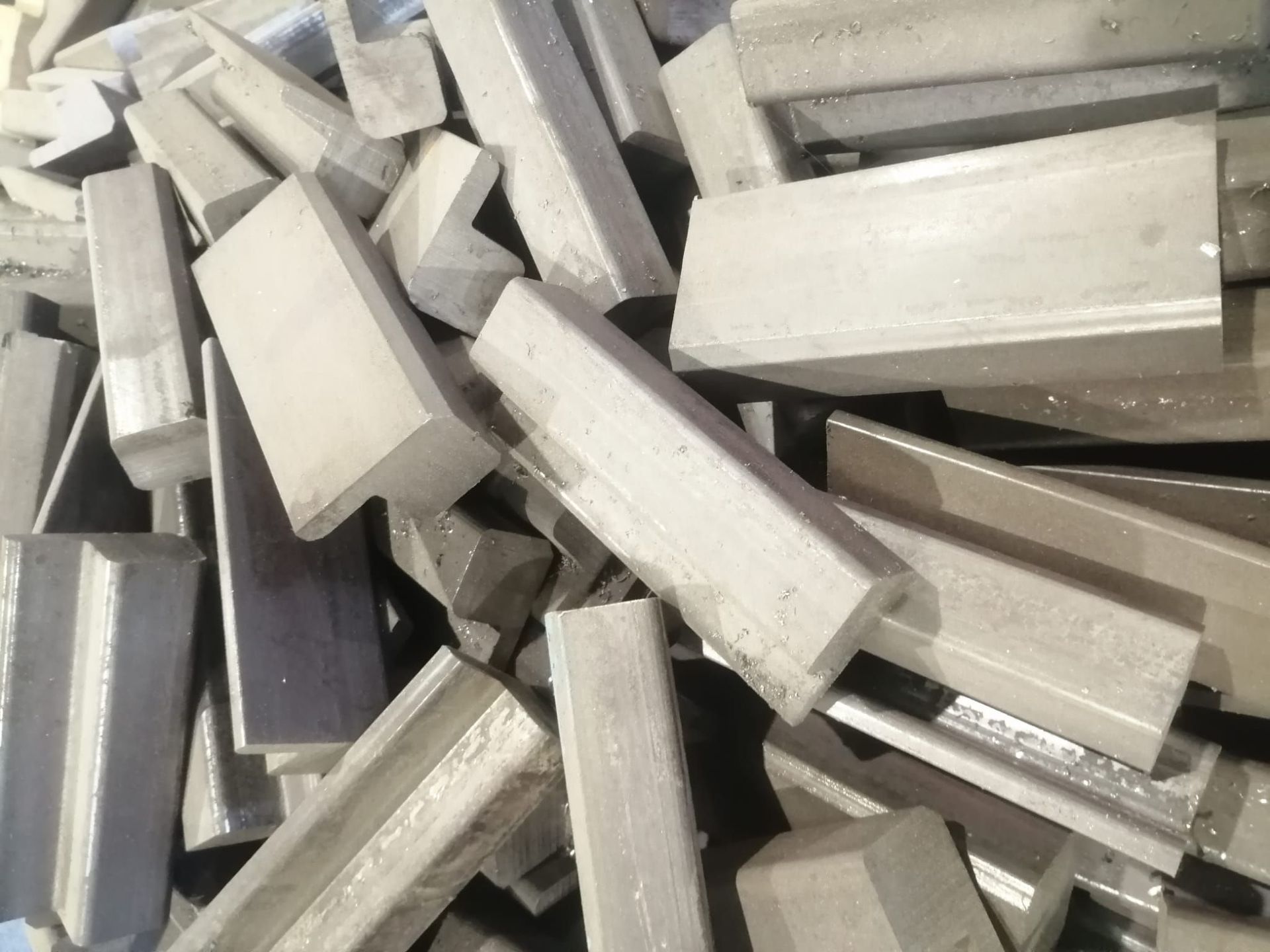 Un mucchio disordinato di lastre o mattoni rettangolari di colore grigio chiaro, impilati in modo caotico.