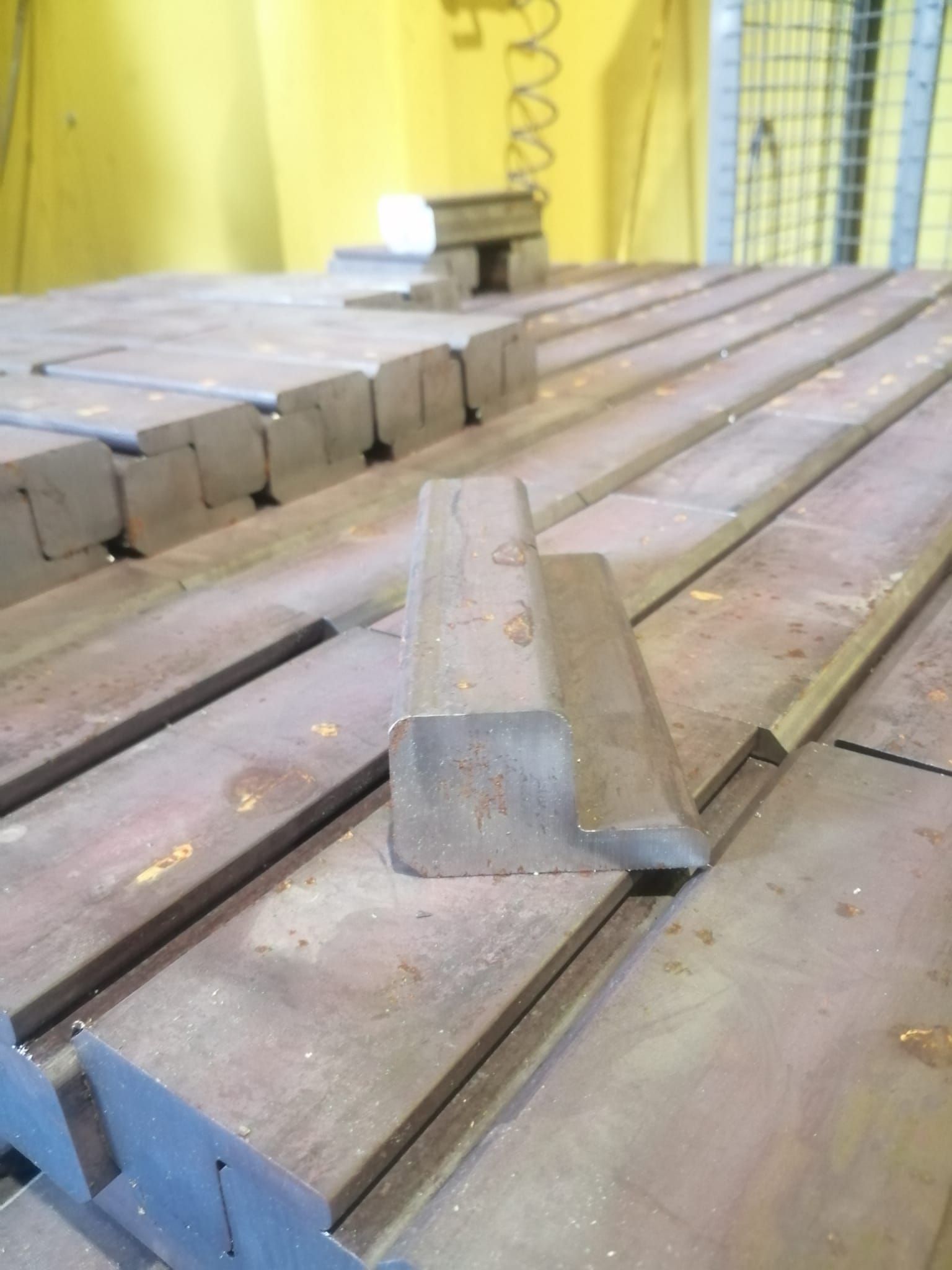 Profili metallici a L disposti su una superficie piana in un'officina industriale.