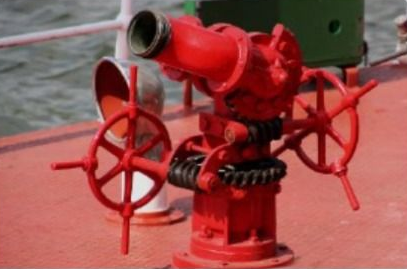 Boquilla de manguera contra incendios de color rojo con dos volantes en la cubierta de un barco.