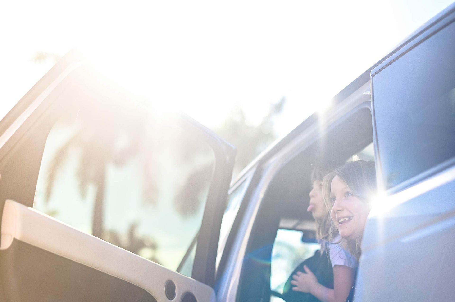 Two girls getting out of a car on a sunny day, highlighting the security auto insurance brings.